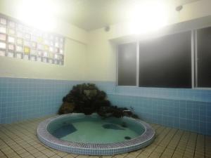 baño con bañera de hidromasaje y fuente de agua en Sunrise Meiji-ya, en Nozawa Onsen