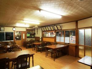 un restaurante vacío con mesas y sillas de madera en Sunrise Meiji-ya, en Nozawa Onsen