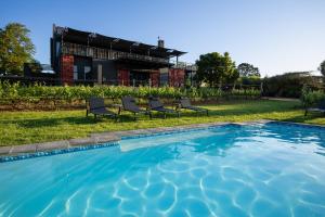 a pool with chairs and a house in the background at Kunjani Villas & Wines in Stellenbosch