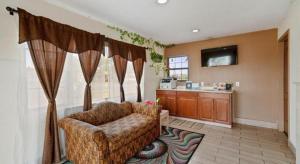 a living room with a couch and a television at Capital O Hotel Beeville - US 181 in Beeville