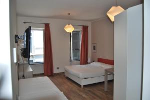 a bedroom with a bed and a table and two windows at Amalia Bakery Home in Gallarate