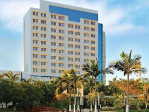 a tall building with palm trees in front of it at Fliport Garden Hotel Xiamen Airport in Xiamen