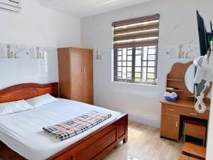 a bedroom with a bed and a desk and a window at Nhà Nghỉ Thành Duy in Quang Ngai