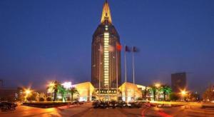 un gran edificio con una torre alta por la noche en New Century Grand Hotel Zhuji Yaojiang, en Zhuji
