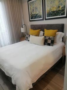 a large white bed with yellow and black pillows at Cosy Regency menylin apartment in Pretoria