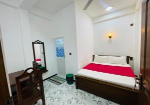 a small bedroom with a bed and a mirror at Aadhira Guest House in Trincomalee
