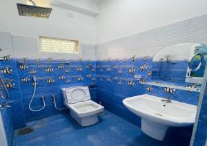a blue bathroom with a toilet and a sink at Aadhira Guest House in Trincomalee