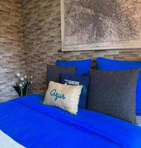 ein blaues Bett mit blauen Kissen im Schlafzimmer in der Unterkunft La Clef du Bonheur - 9 Min de Disney Jardin privatif in Bailly-Romainvilliers