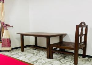 a wooden table and a chair on a rug at Aadhira Guest House in Trincomalee