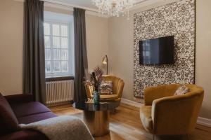 a living room with a couch and chairs and a tv at Home Hotel Grand Helsingborg in Helsingborg