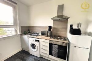 a kitchen with a stove and a washer and dryer at Cosy Apartment In Great Gourock Location in Gourock