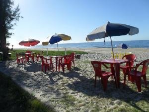 a group of tables and chairs with umbrellas on the beach at Pousada Viva Mar in Saquarema
