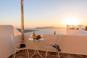 tavolo con bicchieri da vino e vista sull'oceano di Angel Luxury Suites a Firà