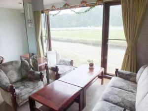 丰冈市Sento Otani Hotel的带桌椅和窗户的客厅