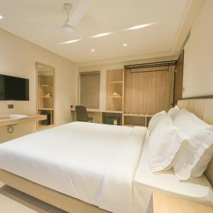 a bedroom with a large white bed and a television at Aarambh By The Sky Imperial Indore in Indore