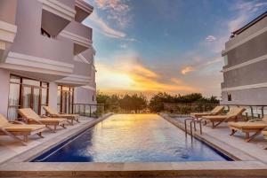 a swimming pool in a building with chairs and a sunset at Wyndham Garden Kuta Beach Bali in Kuta
