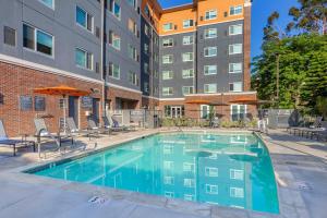 a swimming pool with chairs and a building at Cambria Hotel LAX in El Segundo
