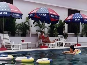 two people in the swimming pool with umbrellas at Quanzhou Overseas Chinese Hotel in Quanzhou