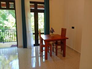 een houten tafel en stoelen in een kamer met een balkon bij SandaLuck House Ahangama in Ahangama