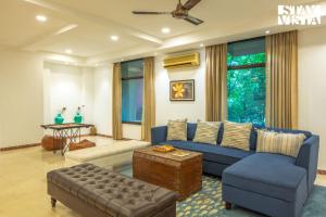 un salon avec un canapé bleu et une table dans l'établissement StayVista at Petals Of Dusk - Outdoor pool, WiFi & BBQ, à Jaipur