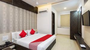 a bedroom with a bed with red pillows and a television at Collection O Kammasandra Gate Bus Terminal Formerly Riches Inn in Bayappanhalli