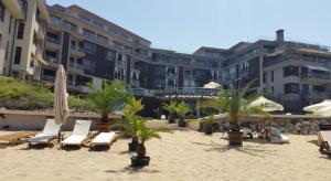 a beach with chairs and umbrellas and a building at Apartment Sand Lilies in Sozopol