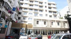 南京市にあるJinjiang Inn Nanjing Xinjiekou Traditional Chinese Medicine Hospital Chaotiangong West Streetの大きな白い建物とその前に駐車された車