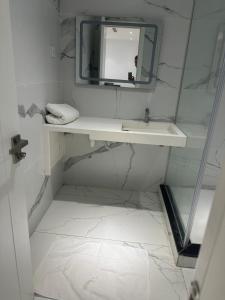 ein weißes Badezimmer mit Waschbecken und Spiegel in der Unterkunft Apartment f2 in Hydra + 11 Fotos