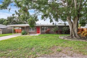 a house with a red door and a tree at Charming 3BR Retreat Near Sarasota Beaches in Sarasota