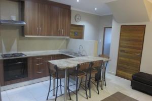 a kitchen with wooden cabinets and a island with bar stools at Waves Echo in Bloubergstrand