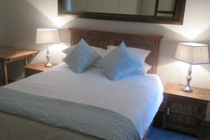 a bedroom with a white bed with pillows and two lamps at Waves Echo in Bloubergstrand
