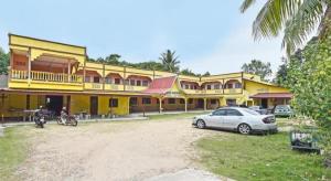 a yellow building with a car parked in front of it at OYO 90454 Haza Harmoni Guesthouse in Kampong Kijang