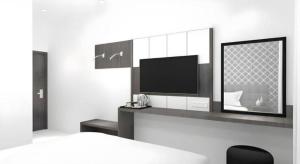 a bedroom with a tv and a bed and a desk at Smart Budget Hotel in Stasiun Tawang