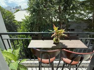 a wooden table with two chairs and a vase with a plant at The Little Danang in Da Nang