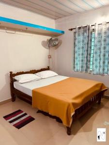 Schlafzimmer mit einem Bett und einem Fenster mit einem Ventilator in der Unterkunft Coffee Voyages in Madikeri