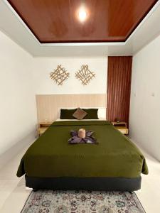 a bedroom with a green bed with a teddy bear on it at Prama Peaceful Living Villa in Ngaglik