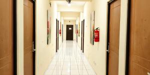 een gang van een hal met witte tegelvloeren en muren bij Grace Setia Hotel in Surabaya