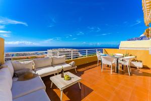 a balcony with couches and tables and the ocean at Eva The View in Puerto de Santiago