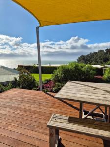 a wooden deck with a picnic table and an umbrella at Bay Vista - glorious Golden Bay Ocean Views in Pohara