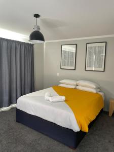 a bedroom with a large bed with a yellow blanket at Bay Vista - glorious Golden Bay Ocean Views in Pohara