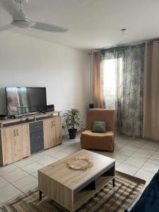 a living room with a tv and a couch and a coffee table at Évasion du lagon, Le patio de la plage St Pierre in Saint-Pierre