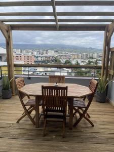 a wooden table and chairs on a deck with a view at Evasion du Lagon in Saint-Pierre