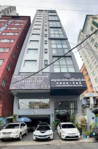 Tres coches blancos estacionados frente a un edificio en Jason Residencia One Hotel, en Phnom Penh