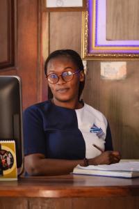 Eine Frau, die an einem Schreibtisch mit Stift sitzt. in der Unterkunft Nile Bridge Cottages in Jinja