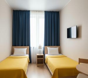 Habitación con 2 camas, cortinas azules y TV. en GozGen Apart, en Alejandreta