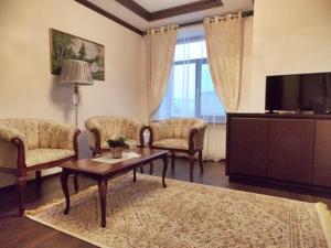 Hotel KREZ في كيزيلوردا: غرفة معيشة مع طاولة وكراسي وتلفزيون