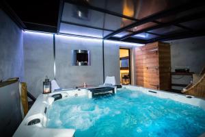 a bathroom with a large tub filled with blue water at Chambres d'hotes Deluxe Jacuzzi Mas de l'Etoile in Aigues-Mortes