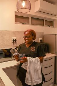 a woman standing in a kitchen holding a glass at Villa Vredenrust Guesthouse in Bloemfontein +93 photos