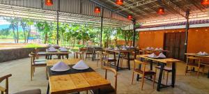 a restaurant with wooden tables and chairs and windows at Sun Hostel and Restaurant Kampot in Kampot