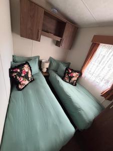 two green beds in a small room with a window at Modern 2017 model Delta Sienna static caravan in Clarach Bay in Aberystwyth +32 photos